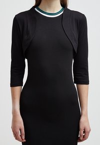 Svart figursytt klänning med trekvartsärmar, med en kort svart överdel vid axlarna. Rund halsringning med blå och vit randig accent.