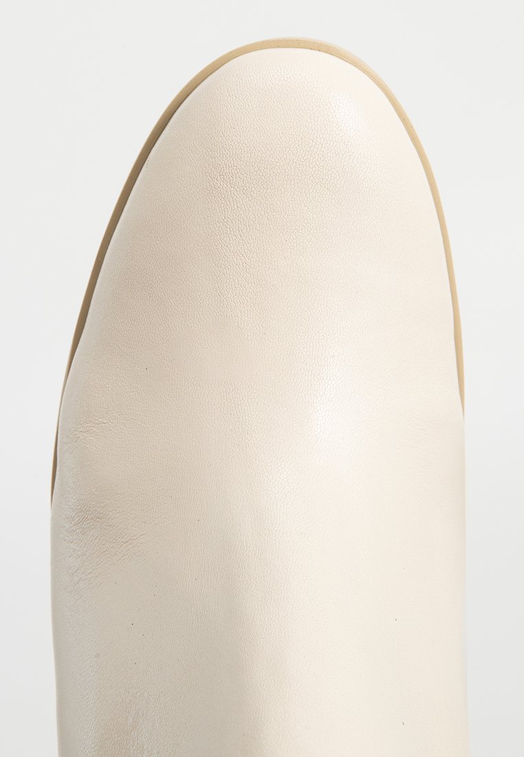 Witte leren enkelboot met een gladde textuur en een ronde neus. Stevig, minimalistisch ontwerp met een naadloos oppervlak en een lichtbruine zool.