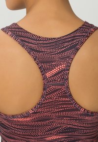 Tummat violetit racerback-urheilutopit, joissa on vaaleanpunaisia täpliä; materiaalina on sileä kangas ja saumatonta rakennetta kaula-aukon ja käsivarsiaukkojen ympärillä.