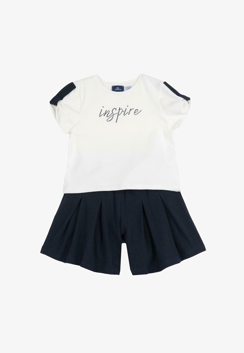 T-shirt en coton blanc à manches courtes, portant le mot "inspire" en strass noirs, associé à un short plissé bleu marine. Texture douce, design décontracté.