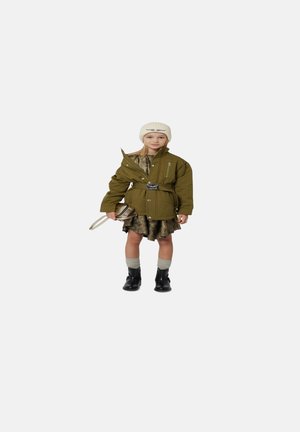 Veste oversize vert olive avec une ceinture, superposée sur une robe dorée, associée à des chaussettes grises jusqu'aux genoux et des bottines noires ; bonnet en tricot crème.