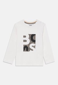 T-shirt blanc à manches longues avec un motif graphique noir et imprimé au centre, encolure ronde et trois boutons pression sur l'épaule.