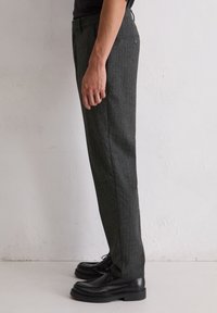 Grijze pinstripe broek met een slim fit, voorzien van een klassieke tailleband en zijzakken, gecombineerd met zwarte schoenen.