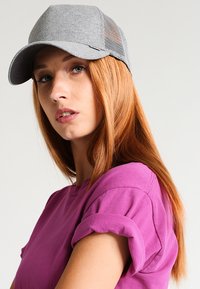 Casquette en mesh grise avec une visière incurvée, dotée d'un tissu léger et de panneaux en mesh sur les côtés. Chemise à manches courtes violette avec des poignets retroussés.