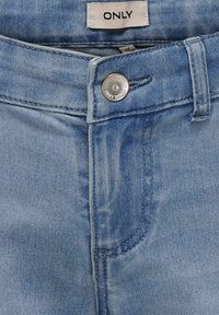 Vaqueros de mezclilla azul claro con una textura suave, presentan un cierre de botón plateado y una etiqueta que dice "ONLY" cerca de la cintura.