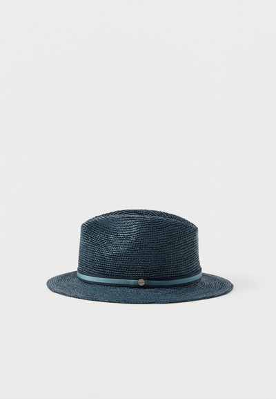 Σκούφο Fedora από σκούρο μπλε πλεκτό άχυρο με ταιριαστή κορδέλα και μικρό μεταλλικό λογότυπο σε απλό λευκό φόντο.