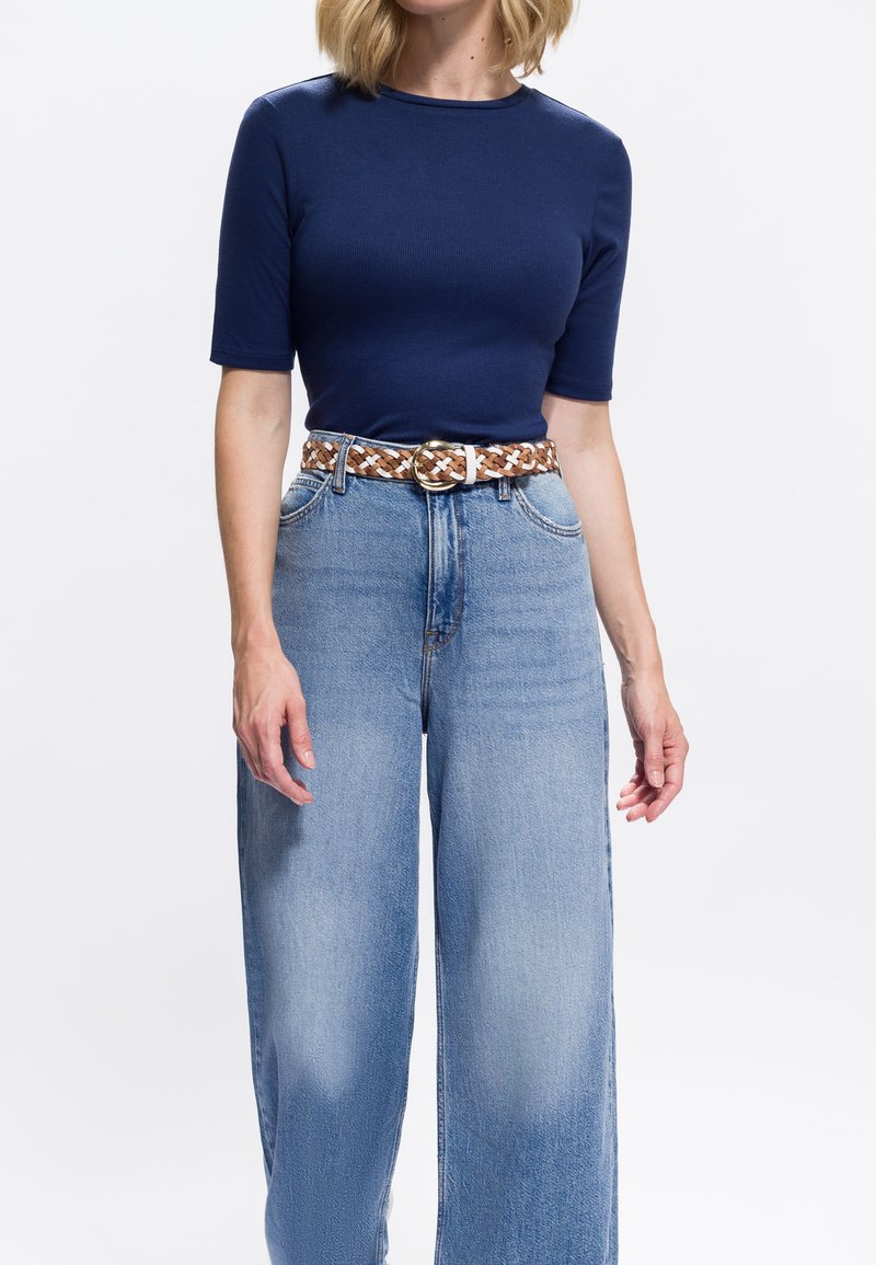 Marineblaue eng anliegende T-Shirt mit kurzen Ärmeln, kombiniert mit hellblauen Jeans mit weitem Bein und einem geflochtenen braun-weißen Gürtel mit goldener Schnalle.