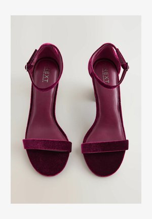 Sandali alti fucsia in velluto con cinturino alla caviglia, ampia fascia frontale e soletta in pelle liscia. Superficie testurizzata e design elegante.