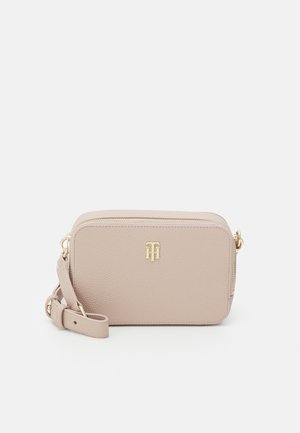 Beige rechthoekige leren crossbodytas met verstelbare schouderriem en goudkleurig metalen logo gecentreerd aan de voorkant.
