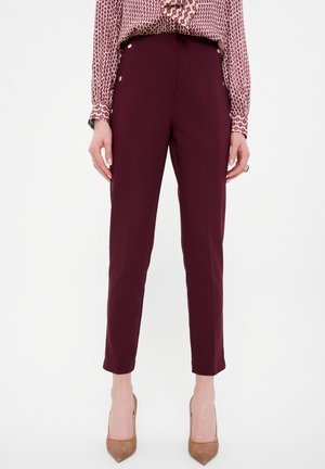 Pantalons ajustés bordeaux avec une coupe slim, longueur cheville, poches slim et accents de boutons dorés à la taille, fabriqués à partir d'un tissu lisse.