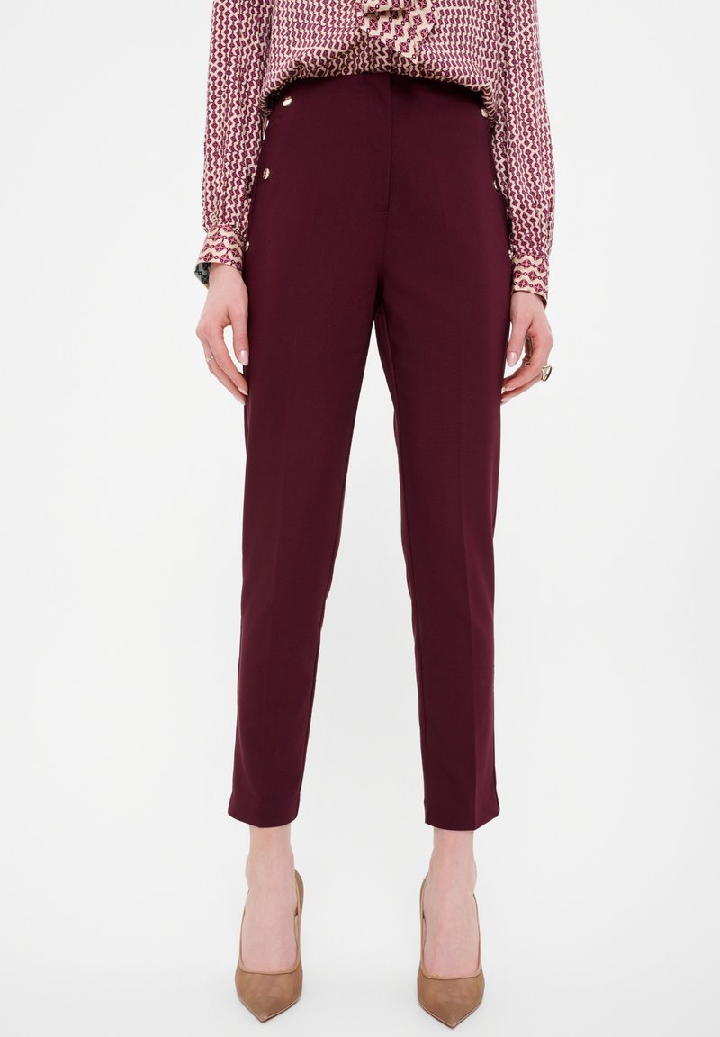 Pantalones tailored burdeos con un corte entallado, longitud hasta el tobillo, bolsillos slim y detalles de botones dorados en la cintura, hechos de una tela suave.