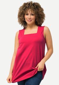 Top sin mangas fucsia con escote cuadrado, hecho de una tela suave, que presenta un corte relajado y un dobladillo asimétrico, combinado con jeans.