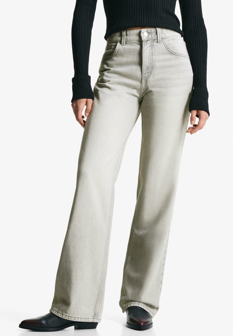Höga vida jeans i ljusgrå denim. Innehåller framfickor och bältesöglor. Matchas med en svart ribbad tröja och svarta stövlar.