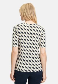 Short-sleeve top in lightweight fabric, featuring a wavy pattern in navy and beige. Crew neckline and relaxed fit, with a smooth texture.