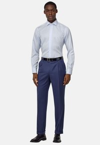 Camisa de vestir a rayas azul claro con cuello puntiagudo; combinada con pantalones oscuros azules, cinturón negro y zapatos de vestir negros y brillantes.