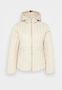 Veste beige matelassée avec une fermeture éclair à l'avant, une capuche et un design matelassé. Dotée d'une taille cintrée et de manches longues. Doublure rayée en accent.