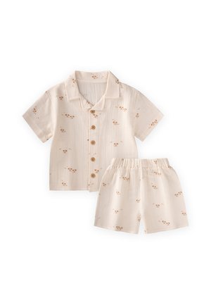 Chemise beige à manches courtes avec boutons et short assorti à taille élastique avec petits motifs floraux marron, posés à plat sur fond blanc.