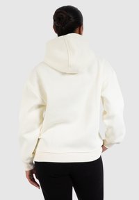 Kapuzenpullover aus Baumwollmischung in Creme, mit großer Kapuze, gerippten Bündchen und Saum. Glatte Textur mit entspanntem Schnitt und überschnittenen Schultern.