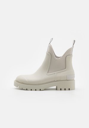 Botas de lluvia Chelsea blancas con un exterior de goma suave, paneles laterales elásticos, una suela con agarre texturizado y una pestaña en la parte trasera para facilitar su uso.