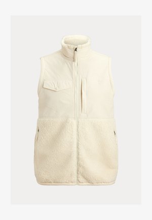 Bezrekawnik w kolorze kremowym z pełnym przednim zamkiem błyskawicznym, wysokim kołnierzem, klapką kieszeni na piersi, pionowym zamkiem na piersi oraz dolną połową z polaru z bocznymi kieszeniami na zamki.