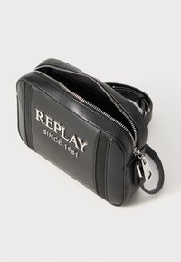 Borsa a tracolla nera in pelle con hardware argentato, dotata di chiusura con zip e logo impresso. Forma rettangolare compatta con tracolla attaccata.