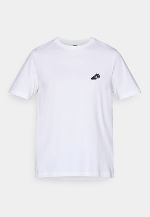 Weißes Baumwoll-T-Shirt mit kurzen Ärmeln und rundem Halsausschnitt; verfügt über eine kleine schwarze Fußballschuh-Grafik auf der linken Brust.