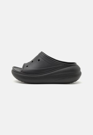 Black slip-on shoe with perforated upper and thick cushioned sole, designed for comfort and casual wear.