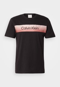 Svart bomulls T-skjorte med en gradient rosa stripe over brystet der "Calvin Klein" er trykt i svart, rund hals, korte ermer.