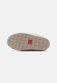 Heled beige sneakeri talla, millel on tekstuuriga muster, kus on lainelised jooned. Keskel punane aktsent. Tasane disain, kummist materjal ja kindel haardevõime.
