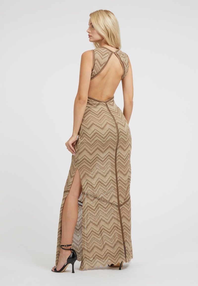 Vestido beige con un patrón de zigzag, diseño espalda al aire y aberturas laterales, hecho de una tela texturizada y combinado con tacones negros.
