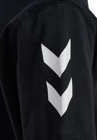 Schwarzes Baumwoll-T-Shirt mit weißen Chevron-Grafiken am linken Ärmel. Der Stoff ist weich mit glatter Textur und bietet eine klassische Passform.