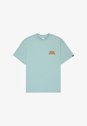T-shirt bleu clair à manches courtes et col rond avec petit logo orange « Quiksilver Since 1969 » sur la poitrine gauche et étiquette logo noire sur la manche gauche.
