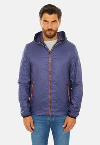 Giacca leggera viola con cappuccio, dettagli di zip rossa e bianca a contrasto, tasche laterali con zip e polsini elasticizzati.