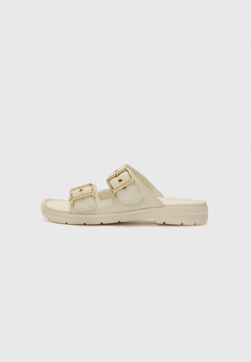 Beige glidesandaler med to gullspenner, myk teksturert overdel, flat såle og et minimalistisk design for hverdagsbruk.