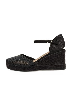 Espadrille negra con cuña, superior de malla tejida, tira en el tobillo y suela texturizada similar al yute. Presenta punta cerrada y parte trasera elevada.