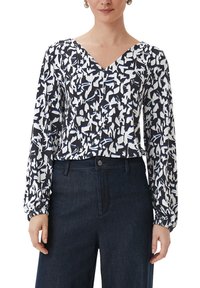 Blusa a maniche lunghe con un motivo floreale astratto in navy e bianco, caratterizzata da una scollatura a V e polsini arricciati. Il materiale sembra leggero e texturizzato.