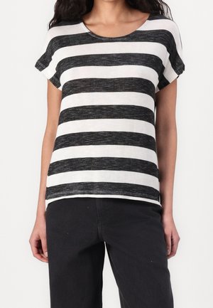 Woman wearing a black and white horizontal striped short-sleeve top and black pants, standing against a white background.