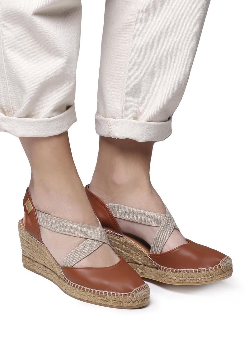 Sandali wedge in pelle marrone con suole in juta intrecciata, dotati di fasce incrociate elastiche e una finitura testurizzata.