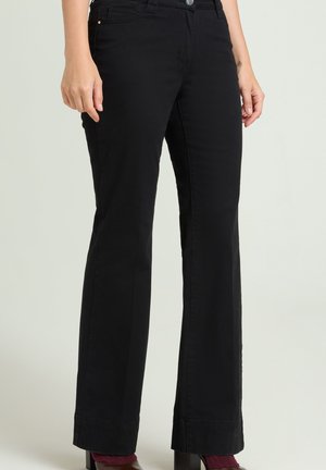 Pantalones negros de pierna recta usados por una persona de pie, mostrando bolsillos delanteros y laterales y cierre de botón en la cintura.