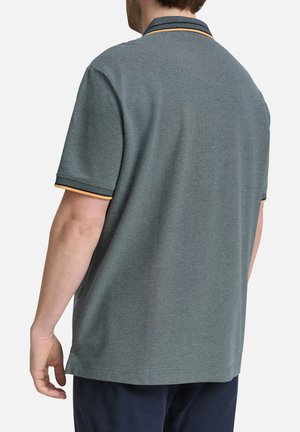 Polo à manches courtes en bleu sarcelle avec un col rayé orange et marine. Confectionné en tissu texturé, il offre une coupe décontractée et des fentes latérales.