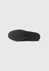 Svart sneakersåle med et mønster for teksturert grep. Flat design, gummimateriale, med en jevn overflate og subtil merkevare.