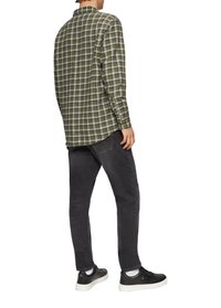 Groen en grijs geblokt overhemd met een button-down kraag, gecombineerd met donkergrijze jeans en zwarte sneakers, gezien van achteren.