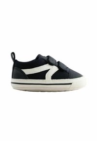 Black canvas sneaker with white accents, velcro straps, and a textured rubber sole. Features a padded collar and a pull tab at the heel.