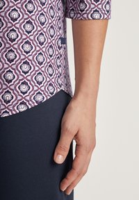 Korte mouw shirt met een roze en marineblauw patroon, met een complexe bloemenmotief; gecombineerd met een donkerblauwe onderkant.