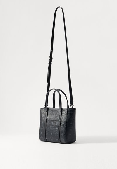 Kleine schwarze Lederhandtasche mit zwei kurzen Griffen und einem langen, verstellbaren Schulterriemen, die mit einem dezenten, geprägten Monogrammmuster versehen ist.