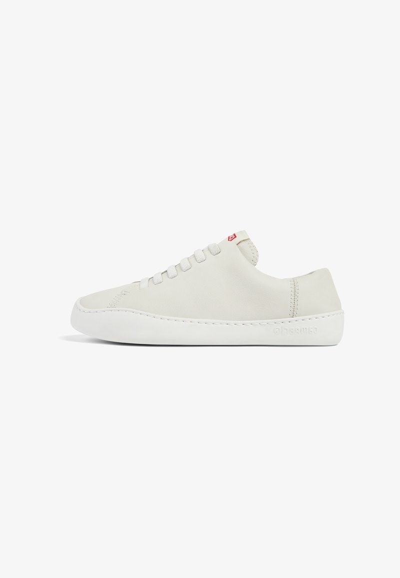 Zapatilla de piel blanca con un perfil bajo, puntera redondeada, cierre de cordones plano y suela de goma blanca. Presenta costuras sutiles y un pequeño logotipo.
