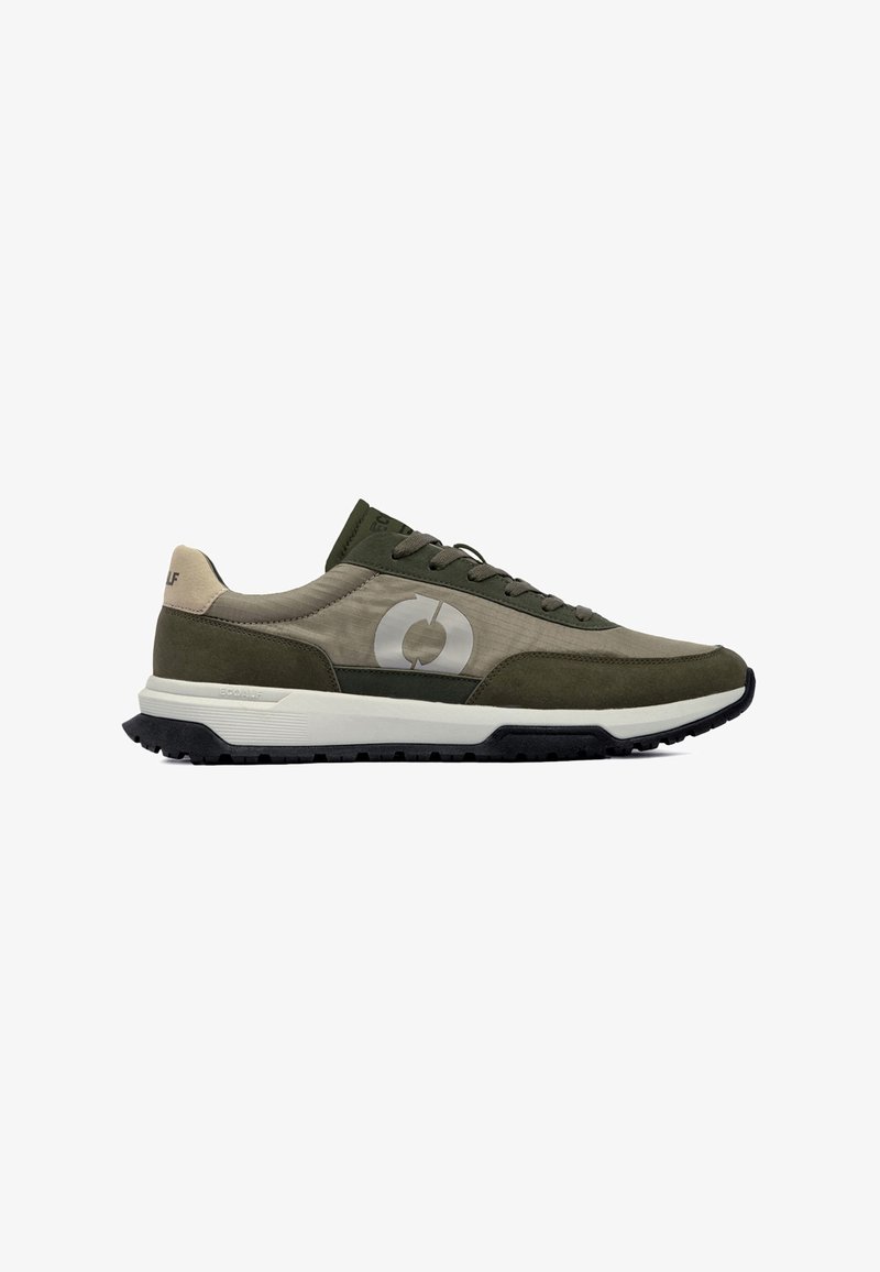 Baskets basses vert olive et beige avec une semelle intermédiaire blanche, une semelle extérieure noire, un laçage avant et un logo circulaire sur le panneau latéral.
