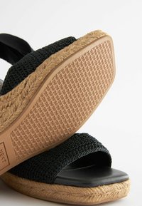 Sandalo espadrille intrecciato nero con suola in corda texturizzata, dotato di una soletta nera liscia e design open toe.
