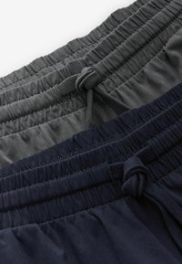 Två par shorts med elastisk midja, en mörkgrå och en marinblå. Båda har snörning och en texturerad tygfinish.