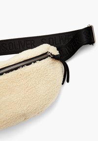 Krémová taška z ovčí vlny s černým popruhem a logem "SOLVER". Zapínání na zip s koženým táhlem. Měkká textura a zaoblený tvar.